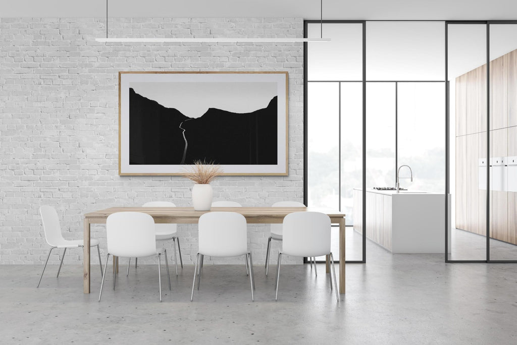 Black and white print of road in Norway hangs in minimal bright white dining room.  thecurrentprintshop.com