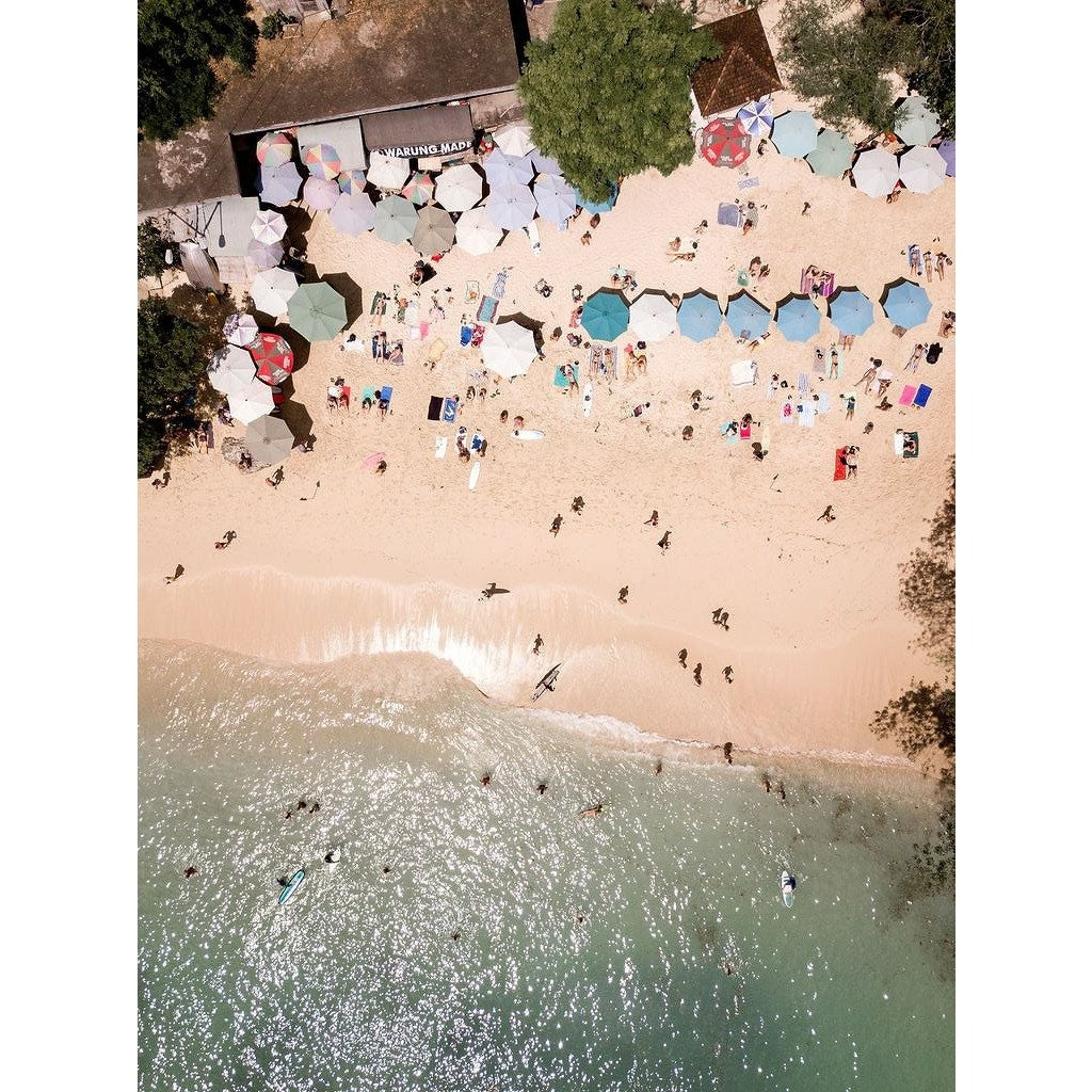 Aerial drone image of beach umbrellas on white sandy beach and tropical waters in Bali, Indonesia.  thecurrentprintshop.com